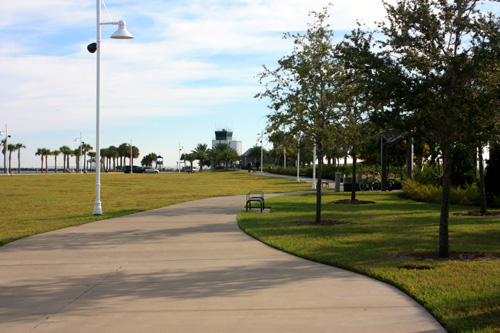 A wide paved walkway surrounds the park. There is plenty of grass for kids to play.