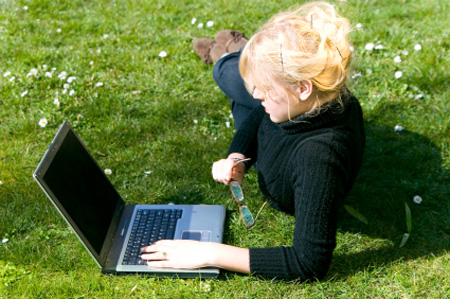 woman working on her travel site in the grass at park she is visiting